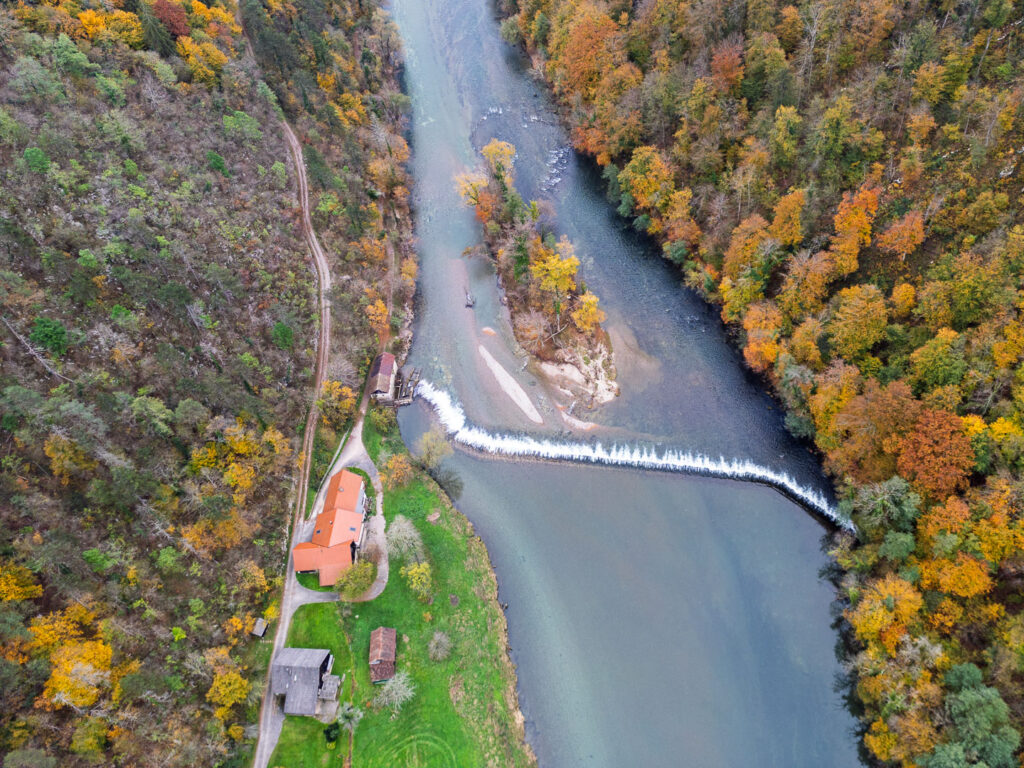 Slika prikazuje posnetek z dronom. Na liki je Breška malenca, jez na reki Kolpi in kolpski otok.